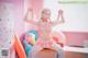 A woman in a pink outfit sitting on a desk.