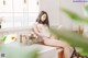 A woman sitting on a kitchen counter next to a sink.