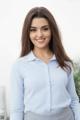 A woman in a blue shirt and gray skirt posing for a picture.