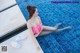 A woman in a pink bikini sitting on the edge of a swimming pool.