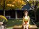 A woman in a yellow kimono sitting on a bench.