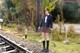 A woman in a school uniform standing on a train track.