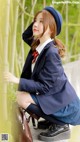 A woman in a school uniform sitting on a ledge.