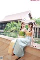 A couple of women sitting next to each other near a pond.