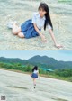 A woman in a school uniform is sitting on a rock.