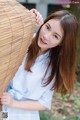 A woman in a blue and white striped shirt leaning against a bamboo fence.