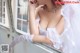 A woman in a wedding dress sitting on a window sill.